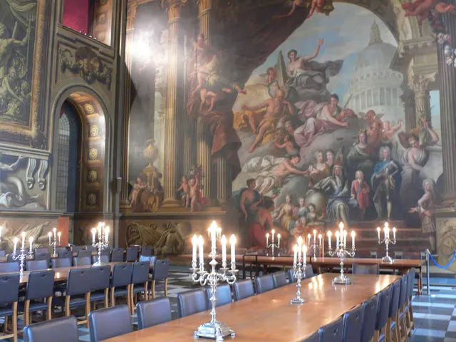 There are tables and chairs. On the table there are candles with stands. In the back there's a wall...