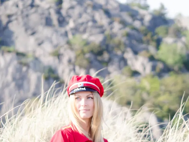 In this image there is a woman sitting on the surface of the grass.